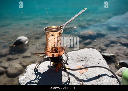 Cuivre Cézve avec café sur un poêle à gaz en automne camping lac dans les montagnes.Préparation du café concept extérieur Banque D'Images