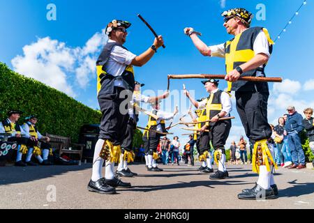 Vue à angle bas regardant le long de deux Rows of Wantsum Morris hommes dansant avec le personnel en bois dans leurs mains au festival de la semaine folklorique de Broadstairs.Ciel bleu. Banque D'Images