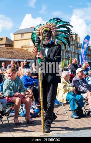 Homme debout dans un costume noir, un noeud papillon et portant un chapeau de plumes indien souriant au spectateur.L'idiot des Bruins et des Bowlers morris Side. Banque D'Images