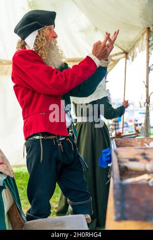 Reconstitution médiévale, vue latérale d'un homme âgé, avec une barbe complète, parlant à une personne non vue, et utilisant ses mains pour représenter les nombres en position debout. Banque D'Images