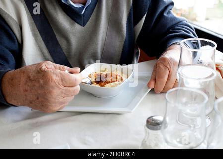 Homme assis à une table mangeant le dessert turc traditionnel de riz (sutlac de firin), dinde Banque D'Images