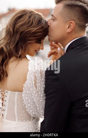 Portraits de 2 amoureux de mariée et de marié. Ils se regardent l'un l'autre, doux au toucher. Jour de mariage, robe de mariage, dos. Moments heureux.Vue latérale Banque D'Images