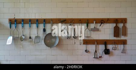Vieux ustensiles de cuisine accrochés au mur blanc de la cuisine Banque D'Images