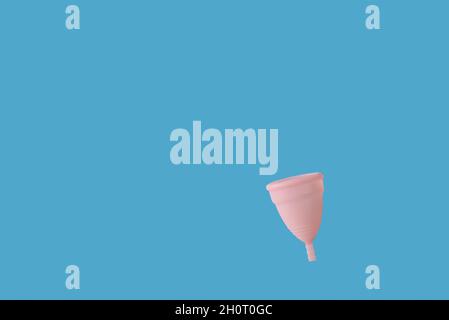 Tasse menstruelle réutilisable rose sur fond bleu Banque D'Images