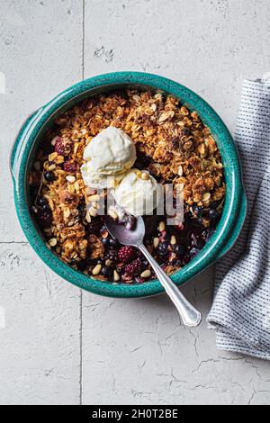 Tarte aux fruits rouges avec crème glacée dans un plat bleu, fond de carreaux gris, vue du dessus. Banque D'Images