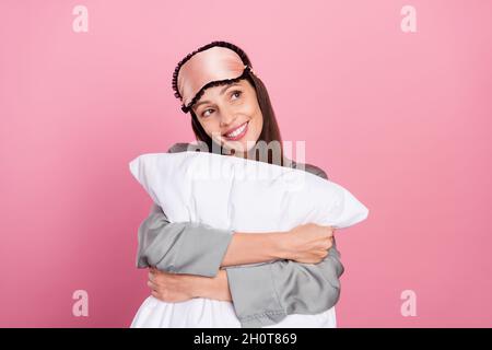 Portrait d'une femme charmante et gaie qui embrasse un oreiller fantastique isolé sur fond rose pastel Banque D'Images