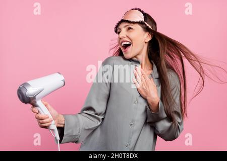 Photo de la femme mature heureux positif sourire sèche-cheveux coiffure vêtements de nuit isolés sur fond rose Banque D'Images