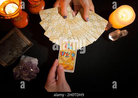 Détail des mains d'une femme montrant des cartes de tarot tandis qu'une autre main montre la "roulette de la fortune" carte face vers le haut.Concept d'une session de divination avec ta Banque D'Images