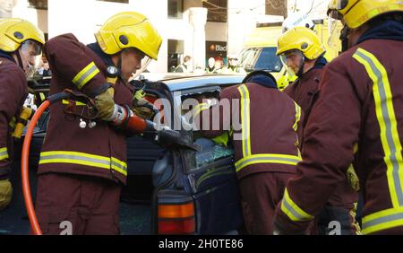 Les pompiers utilisant un équipement de coupe hydraulique pour libérer un occupant emprisonné d'une voiture suite à une collision routière. Banque D'Images