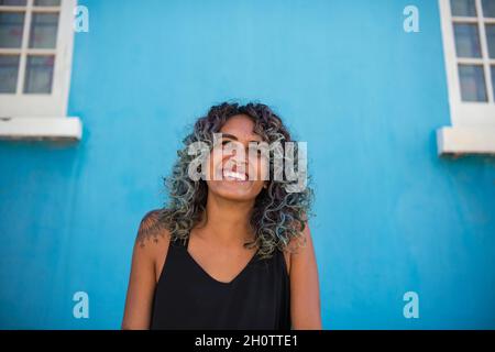 Femme aux cheveux colorés assise avec arrière-plan bleu Banque D'Images