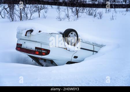 Voiture retournée après un accident dans les montagnes dans la neige profonde après une chute de neige, une vue arrière, des trajets en voiture sur une route de montagne glacée et glissante Banque D'Images