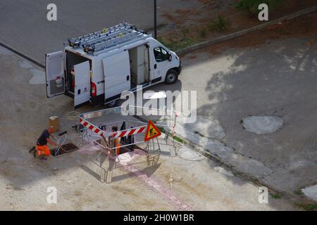 L'employé pose les câbles à fibre optique pour le câblage urbain à l'aide des infrastructures existantes Banque D'Images