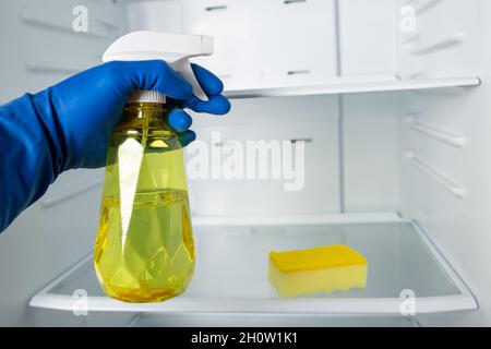 Gants bleus pour nettoyer le réfrigérateur avec un détergent en spray et un morceau de chiffon. Banque D'Images