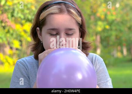 une adolescente a gonflé un grand ballon bleu dans la nature dans le parc. attention sélective Banque D'Images