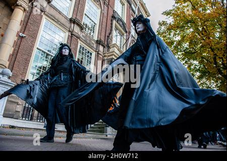 La Haye, pays-Bas.14 octobre 2021.Deux rebelles noirs sont vus se battre contre le vent avec leurs costumes.dans le cadre de la nouvelle campagne de rébellion d'extinction Climate Rebellion,Des centaines de militants du climat se sont promenés dans des vêtements noirs autour du centre de la Haye pour célébrer la mémoire des victimes du changement climatique et de la crise écologique.Le cortège silencieux était dirigé par les rebelles noirs et passé par plusieurs bureaux politiques du parti dans la ville.Crédit : SOPA Images Limited/Alamy Live News Banque D'Images