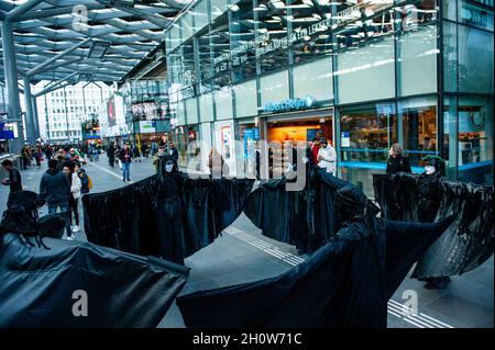 La Haye, pays-Bas.14 octobre 2021.Les Black Rebels sont vus en train de se jouer à l'intérieur de la gare centrale.Dans le cadre de la nouvelle campagne de rébellion contre l'extinction Climate Rebellion, des centaines de militants du climat ont marché dans des vêtements noirs autour du centre de la Haye comme une procession funéraire pour honorer la mémoire des victimes du changement climatique et de la crise écologique.Le cortège silencieux était dirigé par les rebelles noirs et passé par plusieurs bureaux politiques du parti dans la ville.Crédit : SOPA Images Limited/Alamy Live News Banque D'Images