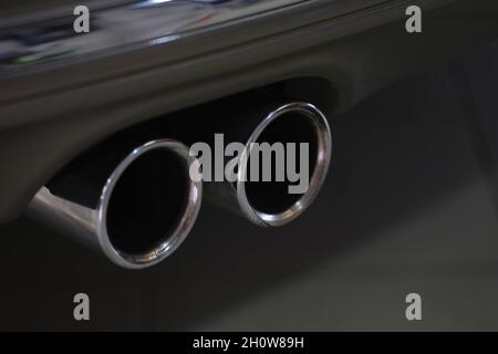 Double tuyau arrière d'échappement chromé d'une puissante voiture de sport avec corps noir et pièces en plastique gris Banque D'Images