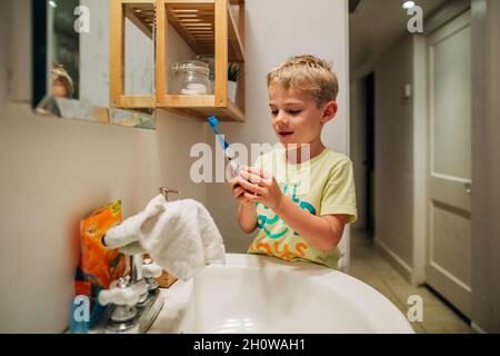 Un jeune garçon se brosse les dents avec une brosse à dents électrique Banque D'Images