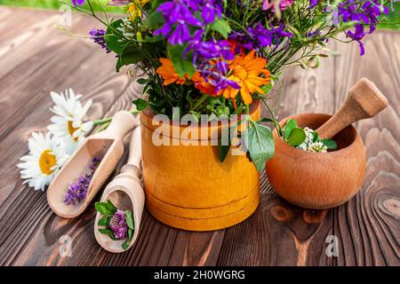 Purple Consolia regalis et orange Calendula officinalis herbes médicinales sur une table en bois près d'un mortier.Faire des potions à partir d'herbes fraîches Banque D'Images