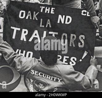 San Francisco 49ers responsable de la sécurité de l'équipe de football lors d'un match contre les Raiders dans le parc de Candlestick de San Francisco en supprimant la bannière « Oakland traîtres » après que les Raiders ont déménagé d'Oakland à Los Angeles, Californie, 1980s Banque D'Images