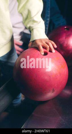 Main d'un garçon qui prend une boule de bowling Banque D'Images