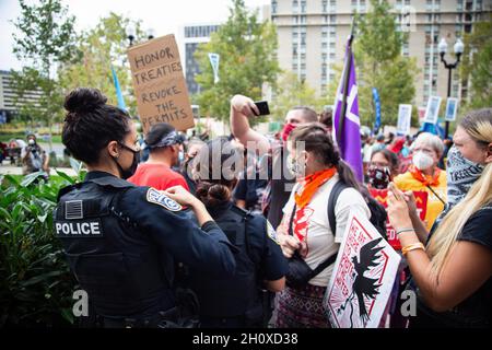 Arlington, États-Unis.13 octobre 2021.Les policiers observent les manifestants pendant la manifestation.Des protecteurs d'eau et des militants autochtones ont manifesté devant l'appartement de Jaime Pinkham du corps des ingénieurs de l'armée des États-Unis lui demandant une réunion pour discuter de la pollution qui ravage l'eau et l'air des communautés des États-Unis.Crédit : SOPA Images Limited/Alamy Live News Banque D'Images