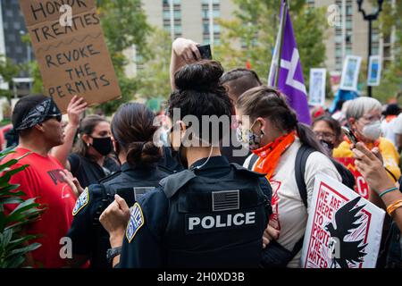 Arlington, États-Unis.13 octobre 2021.Les policiers observent les manifestants pendant la manifestation.Des protecteurs d'eau et des militants autochtones ont manifesté devant l'appartement de Jaime Pinkham du corps des ingénieurs de l'armée des États-Unis lui demandant une réunion pour discuter de la pollution qui ravage l'eau et l'air des communautés des États-Unis.Crédit : SOPA Images Limited/Alamy Live News Banque D'Images