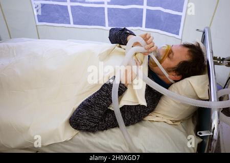 KIEV, UKRAINE - 12 octobre 2021: Les activistes se présentent sur une scène de service de réanimation temporaire pour les patients COVID-19.Homme avec masque à oxygène Banque D'Images