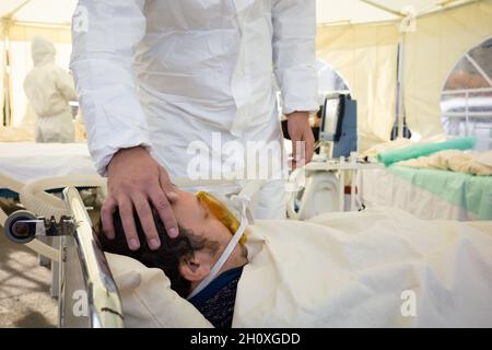 KIEV, UKRAINE - 12 octobre 2021: Les activistes se présentent sur une scène de service de réanimation temporaire pour les patients COVID-19.Homme avec masque à oxygène Banque D'Images