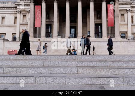 Alors que les passants se précipitent, un busseur joue sa guitare au public sous les colonnes de la National Gallery à Trafalgar Square, le 14 octobre 2021, à Westminster, Londres,Angleterre. Banque D'Images