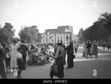 Années 1930, historique, un rassemblement de personnes dans les jardins Bancroft à côté du nouveau théâtre commémoratif de Shakespeare à Stratford-upon-Avon, Angleterre, Royaume-Uni.Le Théâtre commémoratif original avait ouvert sur les rives de la rivière Avon en 1879 et celui vu au loin ici, conçu par une architecte féminine, Elisabeth Scott et sur un site à côté de la rivière originale, ouvert en 1932 .En 1961, il est rebaptisé Royal Shakespeare Theatre, après la création de la Royal Shakespeare Company (RSC) l'année précédente. Banque D'Images