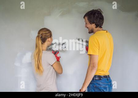 Un homme et une femme plâgent les murs de la maison.Bricolage rénovation maison Banque D'Images