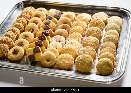 De délicieux biscuits artisanaux sucrés placés sur un plateau argenté sur une table blanche en journée Banque D'Images