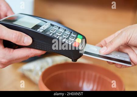 Client et caissier à la caisse pour le paiement mobile avec carte de crédit dans le magasin de matériel Banque D'Images