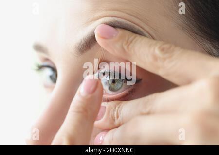 Une femme met des lentilles de contact souples en gros plan Banque D'Images