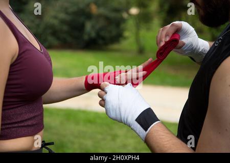 détails mains de l'homme mettant des bandages de boxe sur la femme caucasienne Banque D'Images