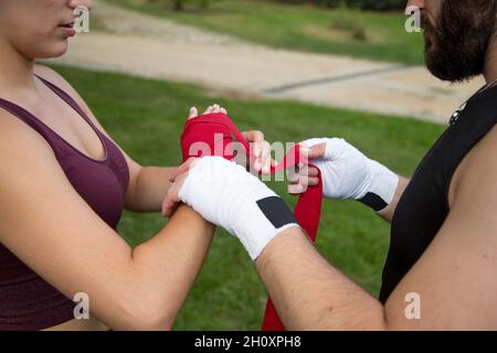 détails mains de l'homme mettant des gants de boxe sur la femme caucasienne Banque D'Images