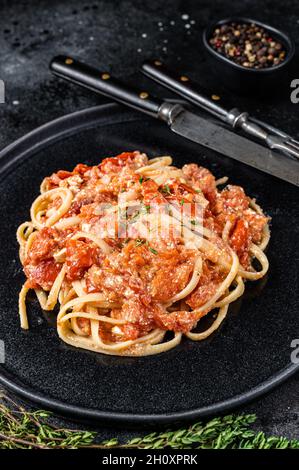 Pâtes Feta tendance avec tomates cerises cuites au four et fromage sur une assiette. Arrière-plan noir. Vue de dessus Banque D'Images