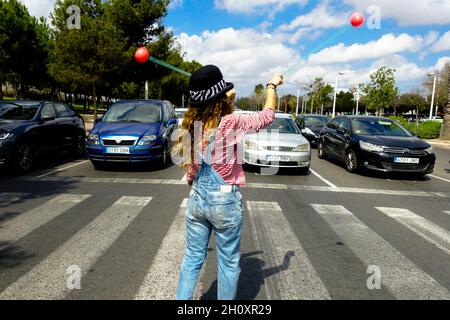 Jeune femme artiste de rue avec des balles sur un passage à niveau pour collecter de l'argent des automobilistes Valencia Espagne Europe Banque D'Images