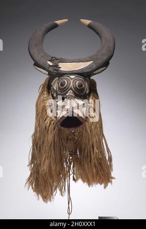 Buffalo Mask, début à mi-1900.Afrique, Afrique de l'Ouest, Burkina Faso, probablement fabricant de style Bwa.Bois, fibres végétales, peinture et fer; total: 69.8 cm (27 1/2 po).Parmi les Bwa, les masques aux traits humains, animaux et fantastiques représentent généralement des esprits protecteurs du Bush.Les cornes et le museau de ce masque l’identifient comme un buffle de brousse.Des danseurs masqués apparaissent pendant la saison sèche à l'occasion d'initiations, de funérailles d'aînés, de journées de marché, de célébrations de récolte et de rituels annuels de renouvellement pour protéger le bien-être de la communauté. Banque D'Images