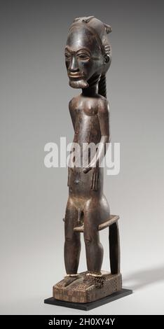 Figure mâle d'une paire (asye usu), de la fin du XIXe siècle au début du XXe siècle.Afrique, Afrique de l’Ouest, Côte d’Ivoire, sculpteur de style Baule.Le bois, la résine, les perles de verre, la fibre végétale et le métal;hors tout : 49.5 x 9.1 x 13 cm (19 1/2 x 3 9/16 x 5 1/8 po).Les figures de Baule sculptées en paires représentent généralement des esprits sans nom du désert appelé asye usu.Ces esprits peuvent intervenir dans la vie des individus en les prenant en possession.Si cette possession n’entraîne pas une folie, elle peut conduire à ce que l’hôte humain devienne un devin qui puisse entrer dans une transe pour révéler les causes des maux et autres malheurs.Péop Banque D'Images