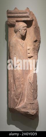 Grave Stela, 400-350 av. J.-C.Grèce, première moitié du 4ème siècle av. J.-C.Marbre pentélique; hors tout: 128.3 cm (50 1/2 po).Sculptée en relief, la composition originale de ce marqueur de tombe attique peut être reconstruite en comparaison avec la célèbre stèle de Hegeso à Athènes.Une femme de ménage, qui tient un pyxis (petit contenant pour les articles personnels) dans sa main gauche, s'approche d'un matron assis habillé d'une himation (cloak).Il manque une grande partie du linteau ci-dessus.Il aurait inclus une inscription avec le nom du défunt.L'humeur est sombre et contemplative sans aucune expression manifeste de deuil. Banque D'Images