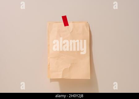 feuille de papier beige vierge, rectangulaire et froissé, collée sur un fond beige clair.Place pour une inscription, annonce Banque D'Images