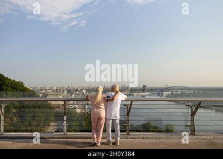 Une femme mûre enjambe l'homme dans la sportsueur se penchant sur la balustrade sur la passerelle contemporaine Banque D'Images