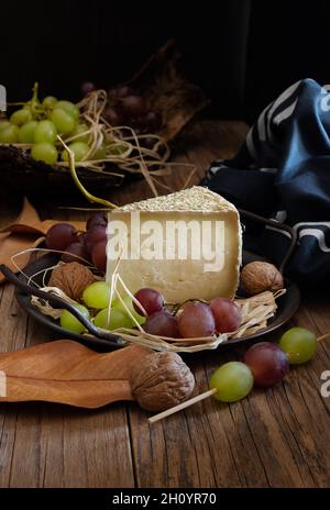 tranche de fromage pecorino avec du foin de montagne, sur fond automnal avec des raisins noirs Banque D'Images