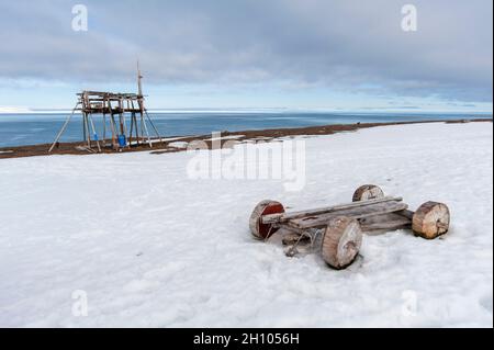 Un stand de chasse et une charrette à roulettes en bois sur une plage enneigée à Mushamna.Île de Spitsbergen, Svalbard, Norvège. Banque D'Images