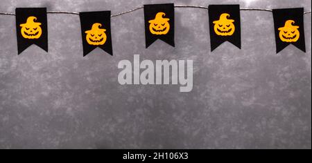 Guirlande pour Halloween.Citrouilles orange aux visages effrayants sur fond noir.Décoration de fête.Bannière.Copier l'espace. Banque D'Images