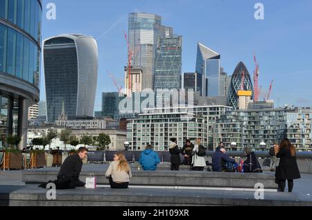 Les gens assis et regardant les gratte-ciel de la ville de Londres comme vu de plus London Riverside. Banque D'Images