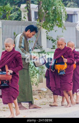 BAGAN, MYANMAR - 8 DÉCEMBRE 2016: Rangée de jeunes moines bouddhistes avec des bols collectant leurs almes quotidiens. Banque D'Images