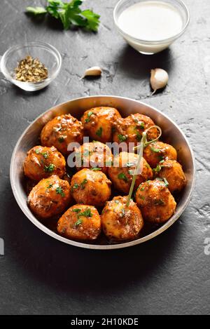 Faire frire les petites pommes de terre frites avec des graines de jeera et de la coriandre dans un bol sur fond sombre.Plat indien populaire. Banque D'Images